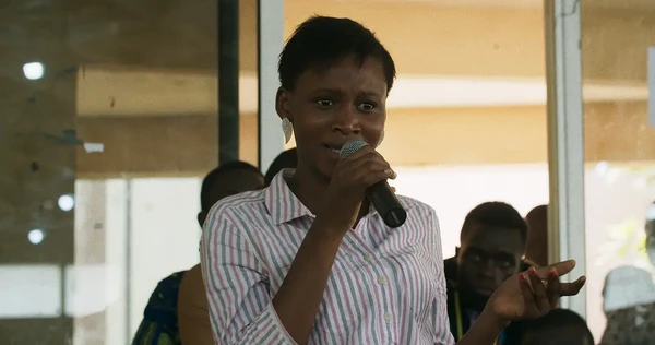 A woman speaks passionately with a microphone in the documentary "Dahomey".