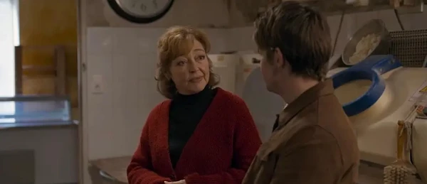 A woman and a man engage in conversation in a room in the film "Miséricorde".