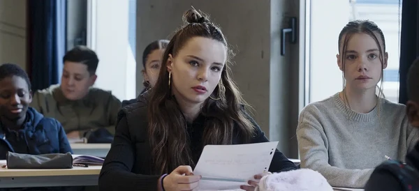 A student holds paper, looking pensive in a classroom scene from "Pas de vague".