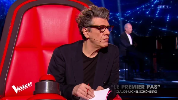 A mentor sits in the iconic red chair, judging in "The Voice: La Plus Belle Voix".