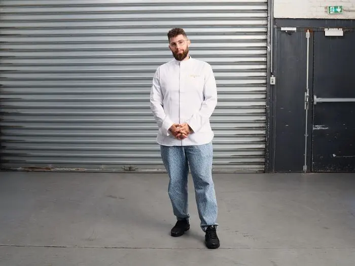 A chef poses confidently in a casual yet professional look in "Top Chef France".