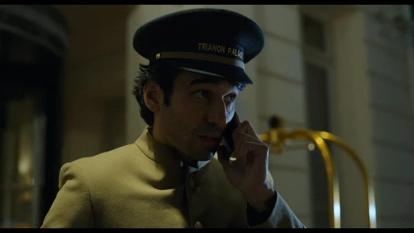 A doorman talks on the phone outside a building in Ad Vitam.