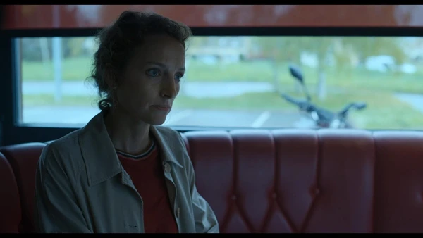 A woman sits thoughtfully in a vehicle in Ad Vitam.